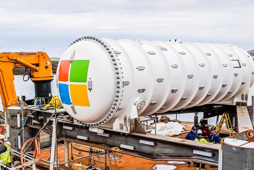 A photo of a large metal tube with the Microsoft logo, preparing to be submerged. This is the Project Natick data center.