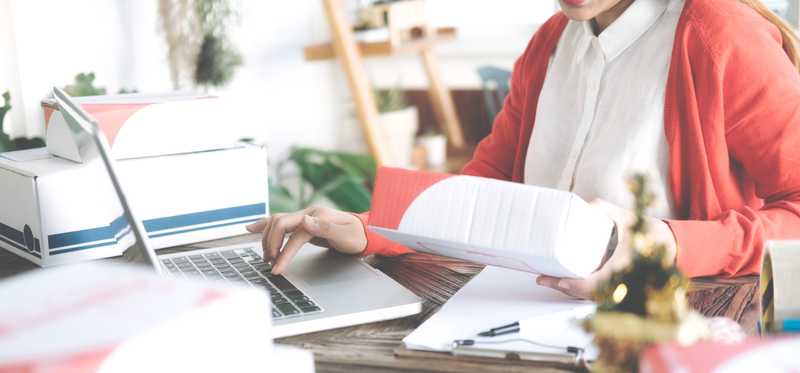 Woman typing in laptop and holding small box