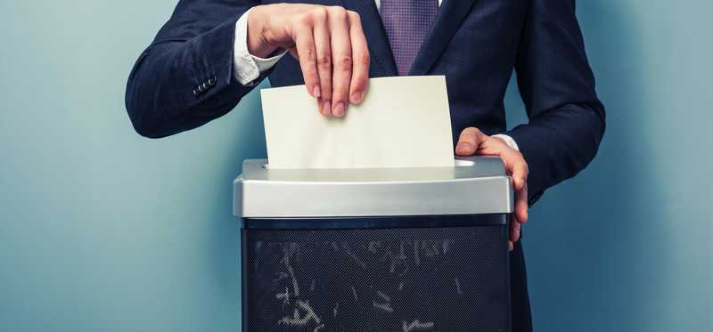 Headless person in tie shredding paper.