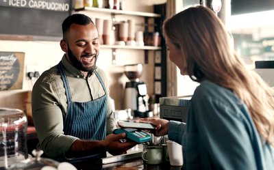 Barista accepting a digital payment from a customer in a cafe.