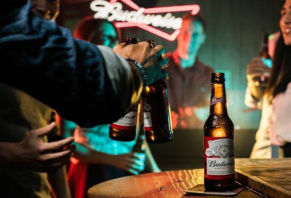 people drinking bottles of Budweiser beer in a bar