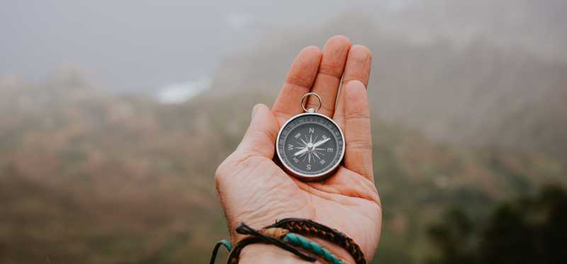 Person holding compass in hands outdoors.