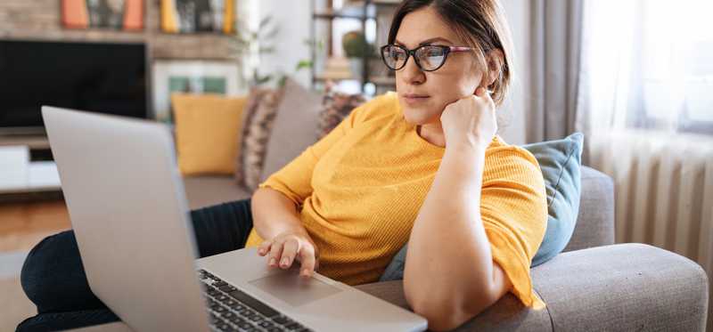 Person sitting in armchair while using laptop.