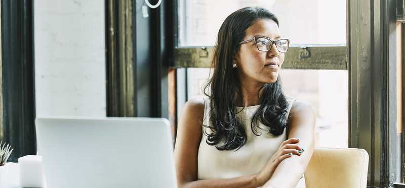 Person at desk with laptop is looking out window.