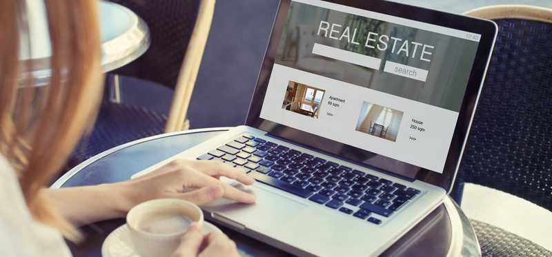 A person at a laptop looking at Real Estate on the screen.