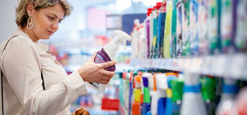 A person selecting cleaning spray at a grocery store.