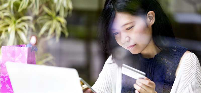 A person with a credit card, laptop, and phone.