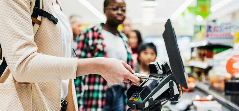 Person in store using digital payment at register.