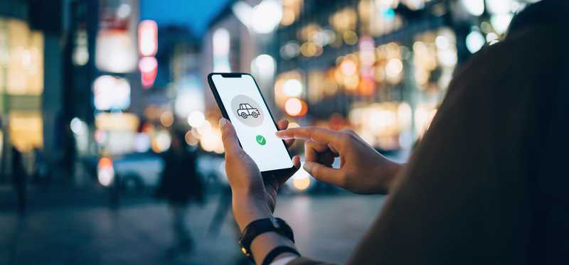Person using ridesharing app on city street.
