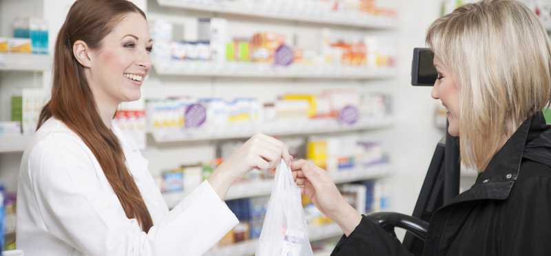 A woman receives her prescription from a pharmacist.