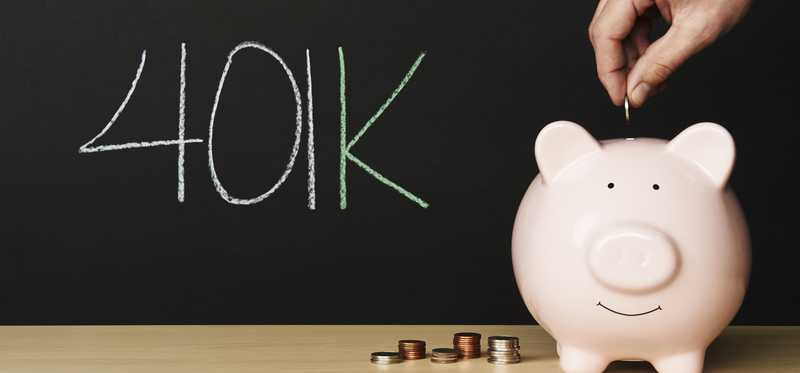 Piggy bank and stacks of coins in front of blackboard with 401k written on it.