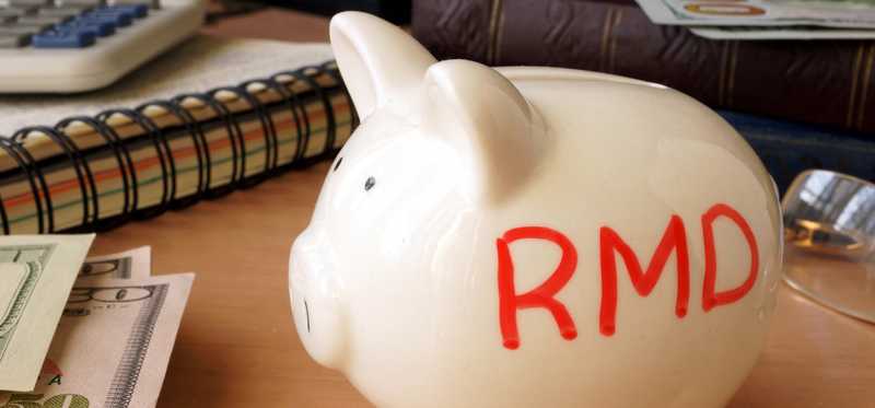 Piggy bank with RMD written on its side next to stack of paper money.