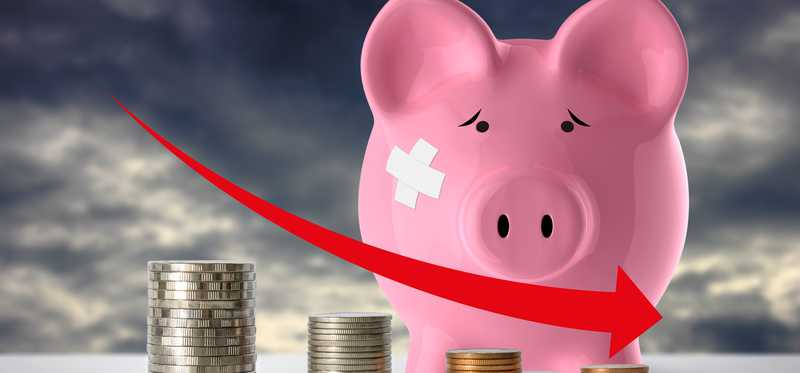 Piggy bank with bandage and declining coin pile