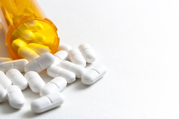 A prescription bottle overturned with pills pouring out.