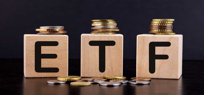 Coins sit atop of wooden blocks that spell out ETF.