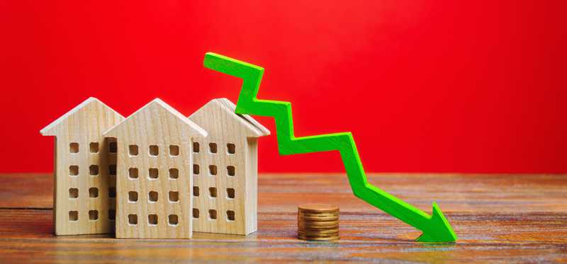 Arrow trends down over houses and coins.