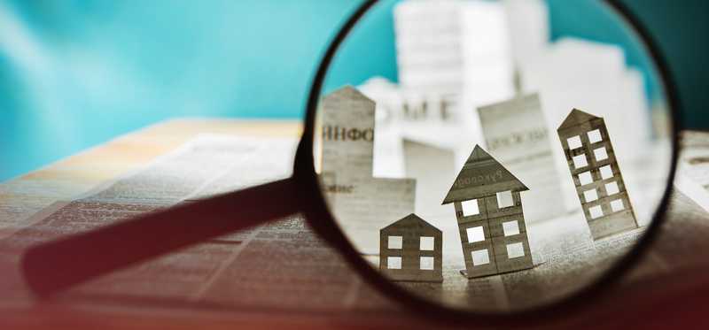 Magnifying glass over paper cutouts of different types of housing.