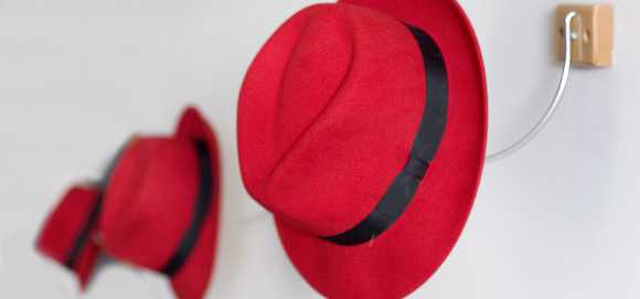 A row of red fedora hats hang on hooks.