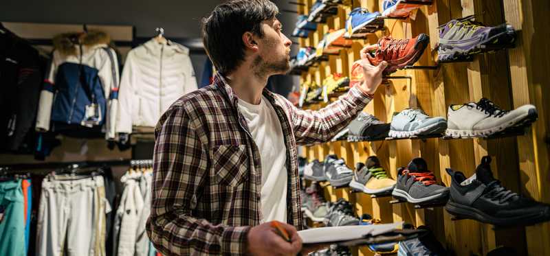 A person with a clipboard doing inventory in a retail shoe store.