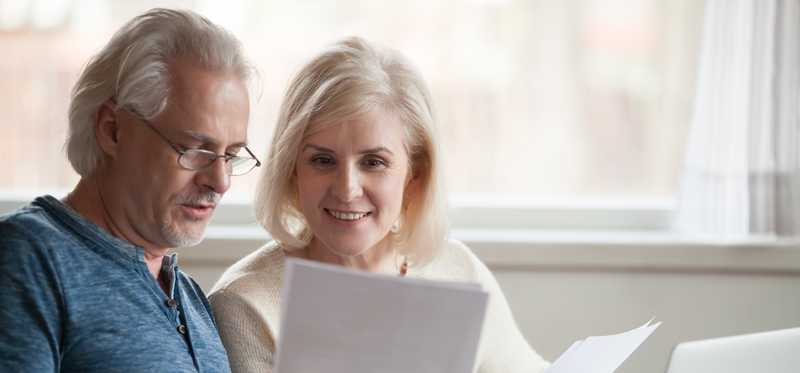 Two people review documents in front of laptop at home.