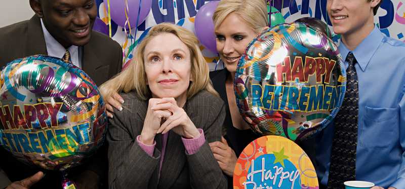Office workers surround retiree at retirement party.