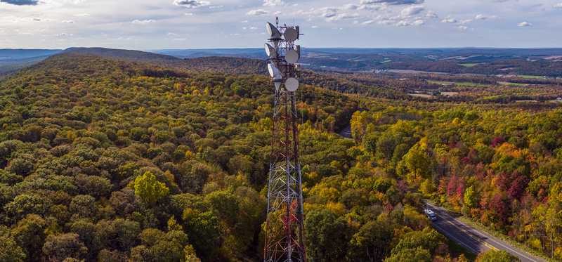 A cell tower overlooking a forested area.