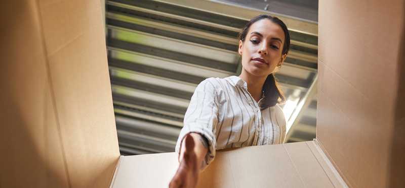 Person packing a box in a self-storage unit.