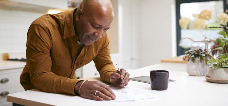 Person works on paperwork at kitchen counter.