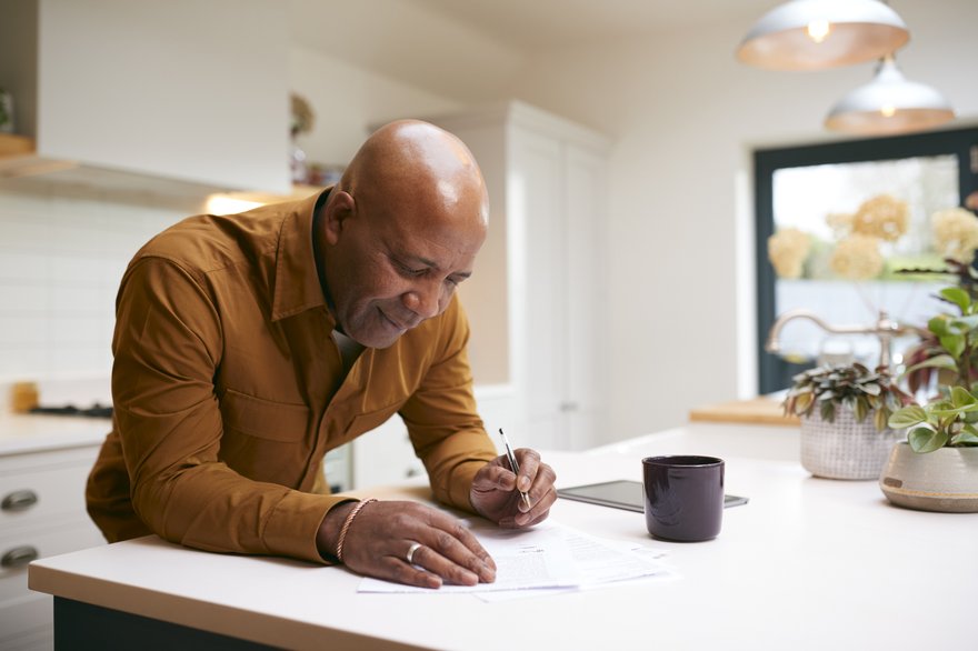 Person working on paperwork at kitchen counter.