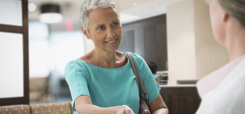 Person smiles while presenting an insurance card at doctor's office.