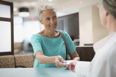 Person smiles while presenting an insurance card at doctor's office.