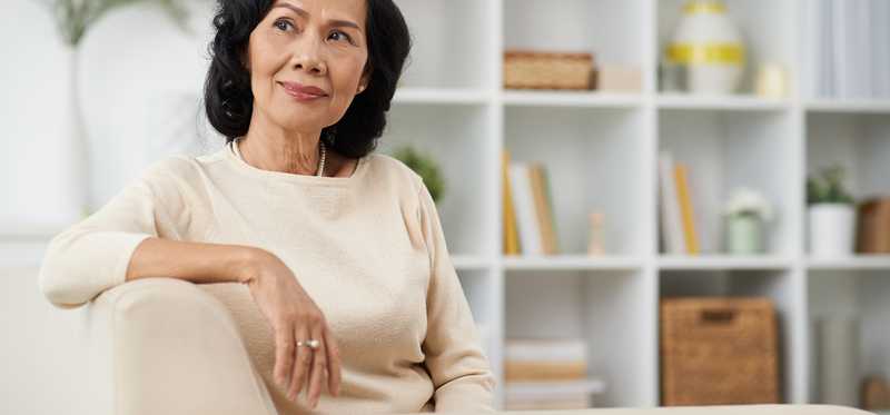 Senior woman sitting on couch and thinking