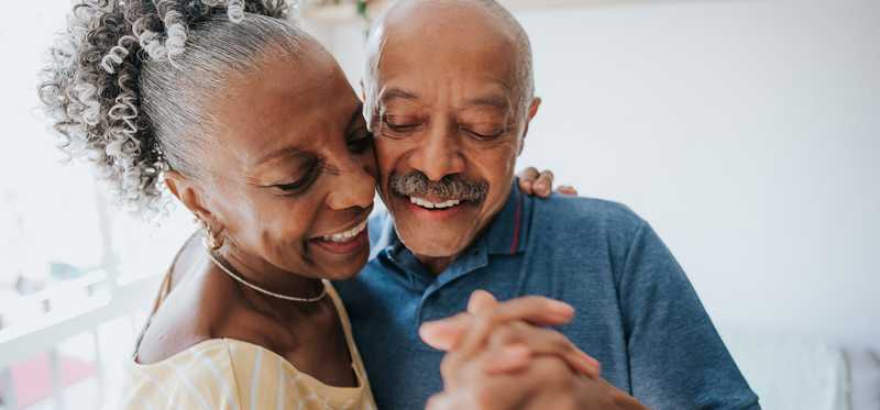 Two people happily dancing at home.