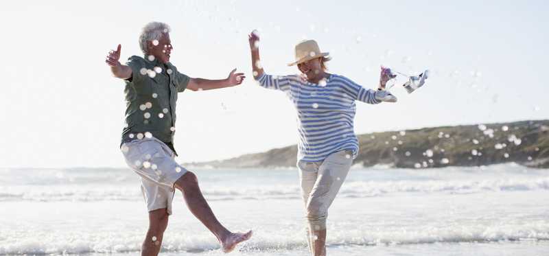 Senior couple splashing in ocean by beach