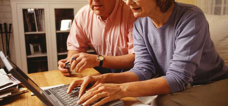 Senior couple using laptop and credit cards.