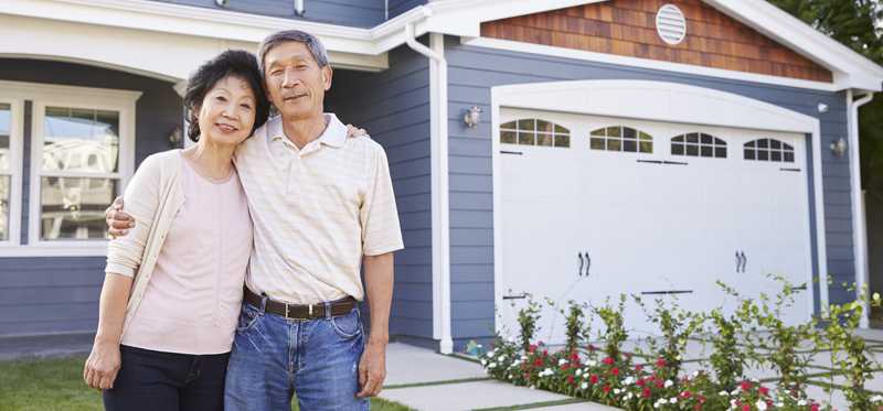 Two people standing outside a house with their arms around each other.