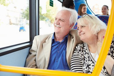senior man and woman sitting on bus and smiling