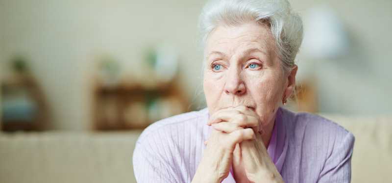 Senior woman worried thinking with hands clasped in front of face