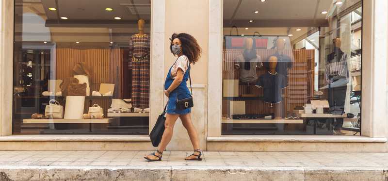 A person walking by some storefronts.