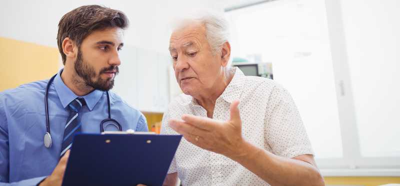 Young male physician talks with elderly man.