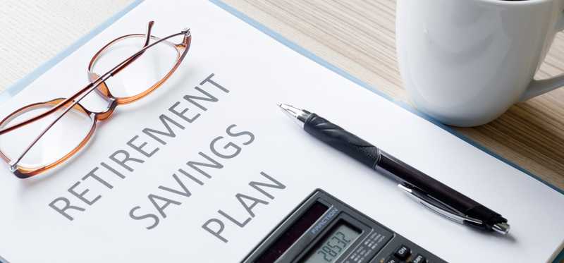 Paper titled Retirement Savings Plan with pen, reading glasses, and coffee nearby.