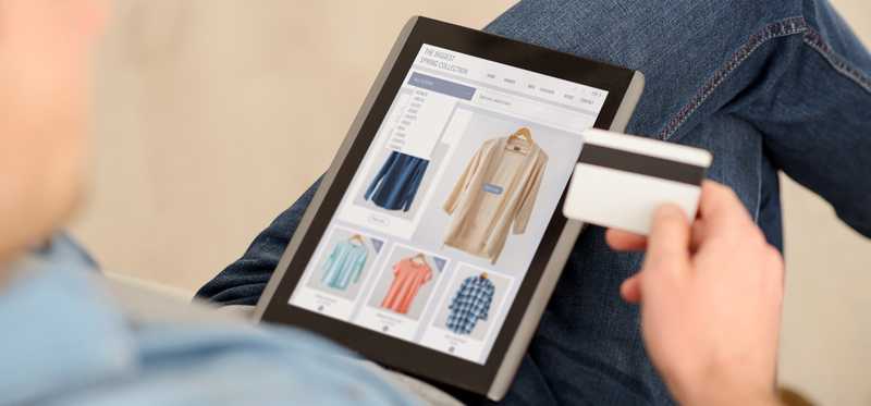 Person shopping online on a tablet while holding a credit card.