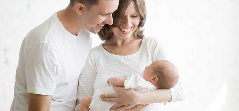 A young couple holds a newborn.