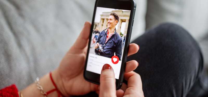 Person holds phone showing dating app.