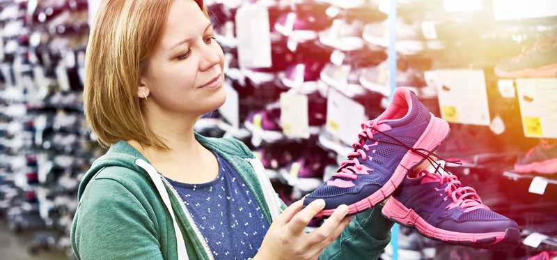 Woman inspecting a pair of athletic shoes in a shoe store