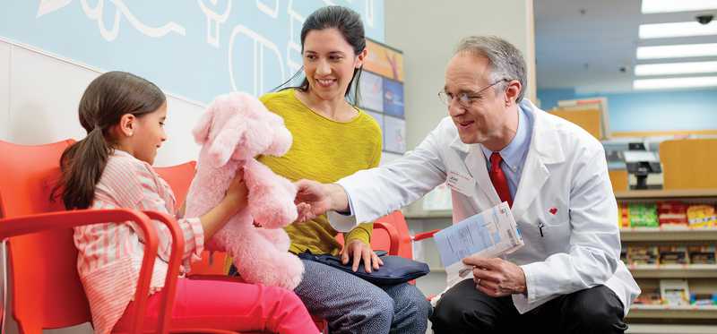 A CVS associate talks to a child near the pharmacy seating area.