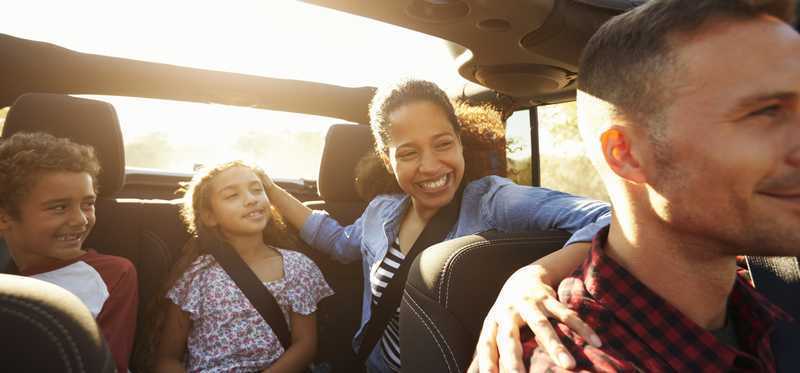 Happy family in a car with sunroof open.