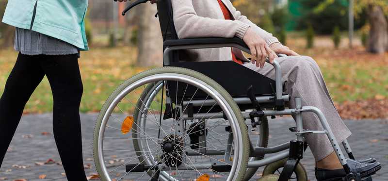 Woman pushing man in a wheel chair.