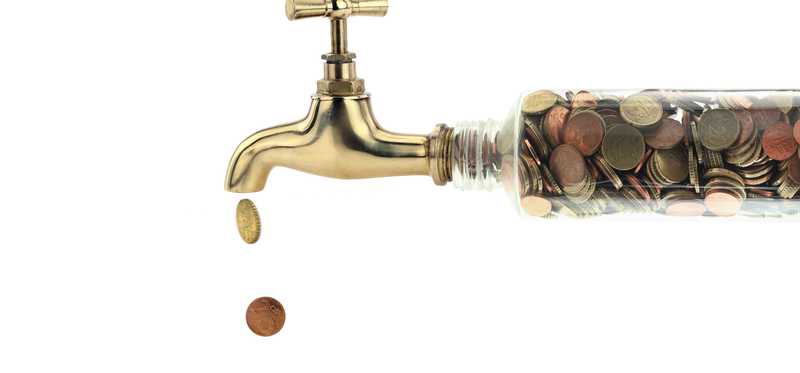 A faucet with clear pipes filled with coins.