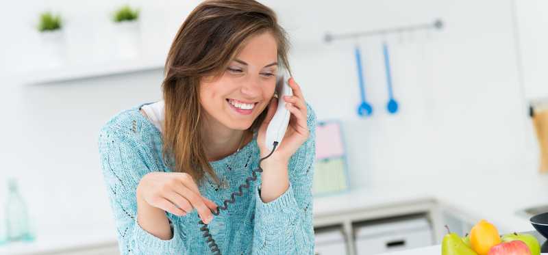 A person talking on the phone in the kitchen.